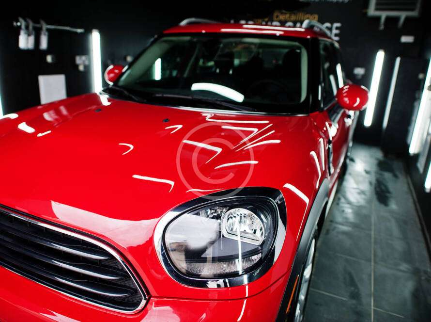 Shiny red car with detailed headlight in a showroom.