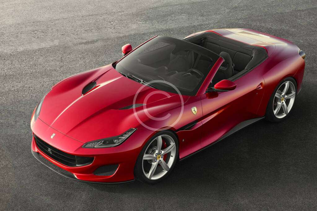 A sleek red Ferrari sports car parked on a gray surface.