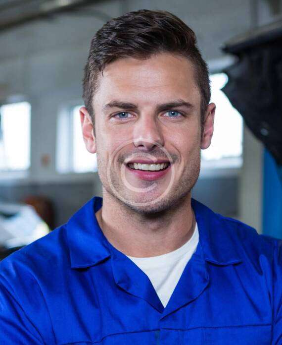 A man in a blue work uniform smiling confidently.