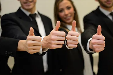 Group of people giving thumbs up in business attire.