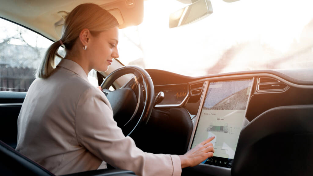 Woman using touchscreen in modern car interior.